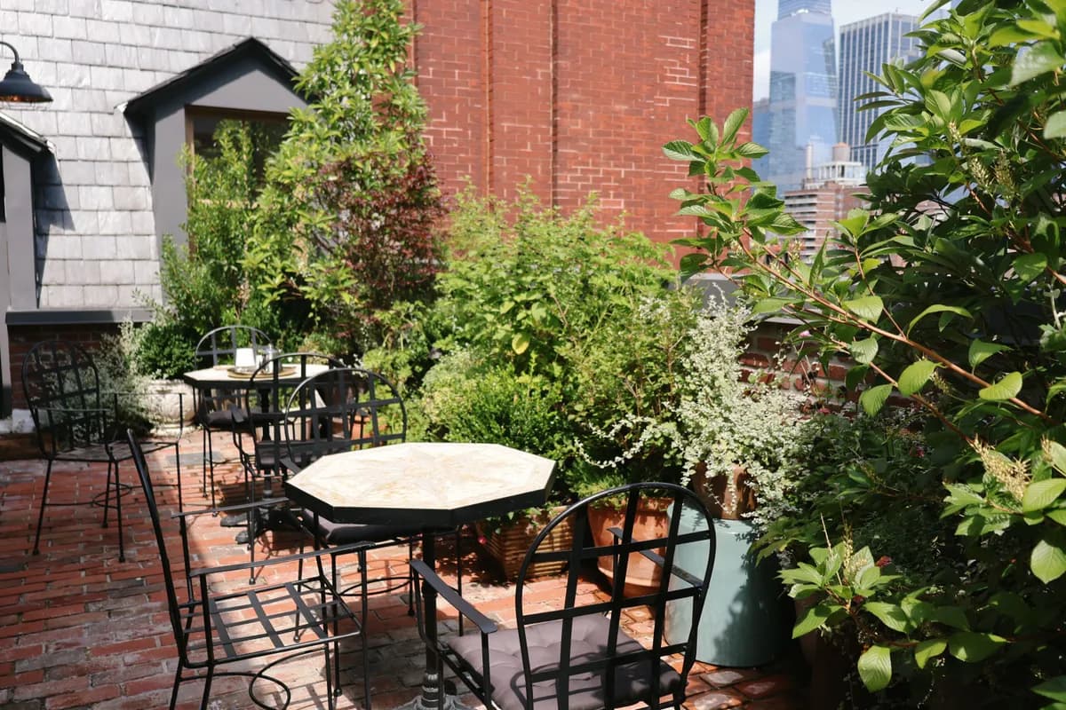 BookNoFees Beispielbild: Begrünte Dachterrasse mit runden Tischen und Stühlen