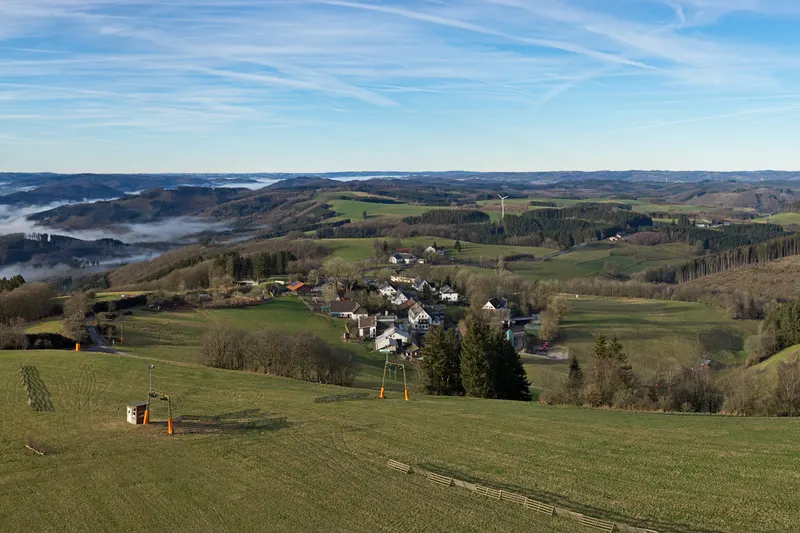 Die Wildewiese in den Hügeln des Sauerlands, mit einem Skilift auf der Wiese und dem Dorf darunter