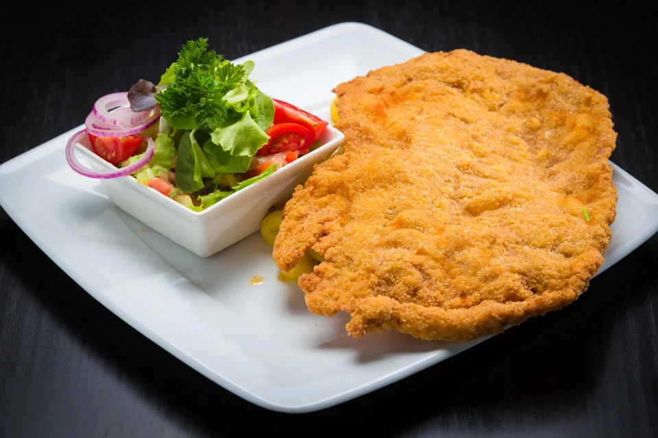 BookNoFees: Beispielfoto: Paniertes Schnitzel mit Beilagensalat auf einem weissen Teller