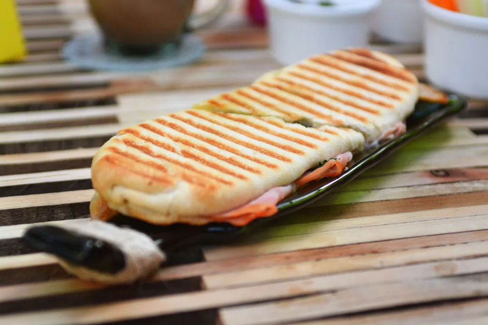 BookNoFees: Beispielfoto: Ein geröstetes Panini mit Grillstreifen auf einem dunklen Teller
