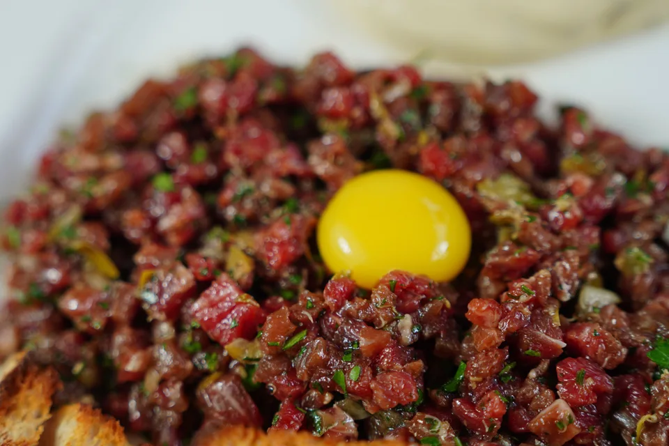 BookNoFees: Beispielfoto: Steak Tartar mit Eigelb garniert und mit geröstetem Brot serviert
